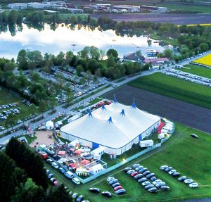 Palastzelt mit 6 Masten, aufgebaut in einer Landschaft, im Hintergrund ist ein See